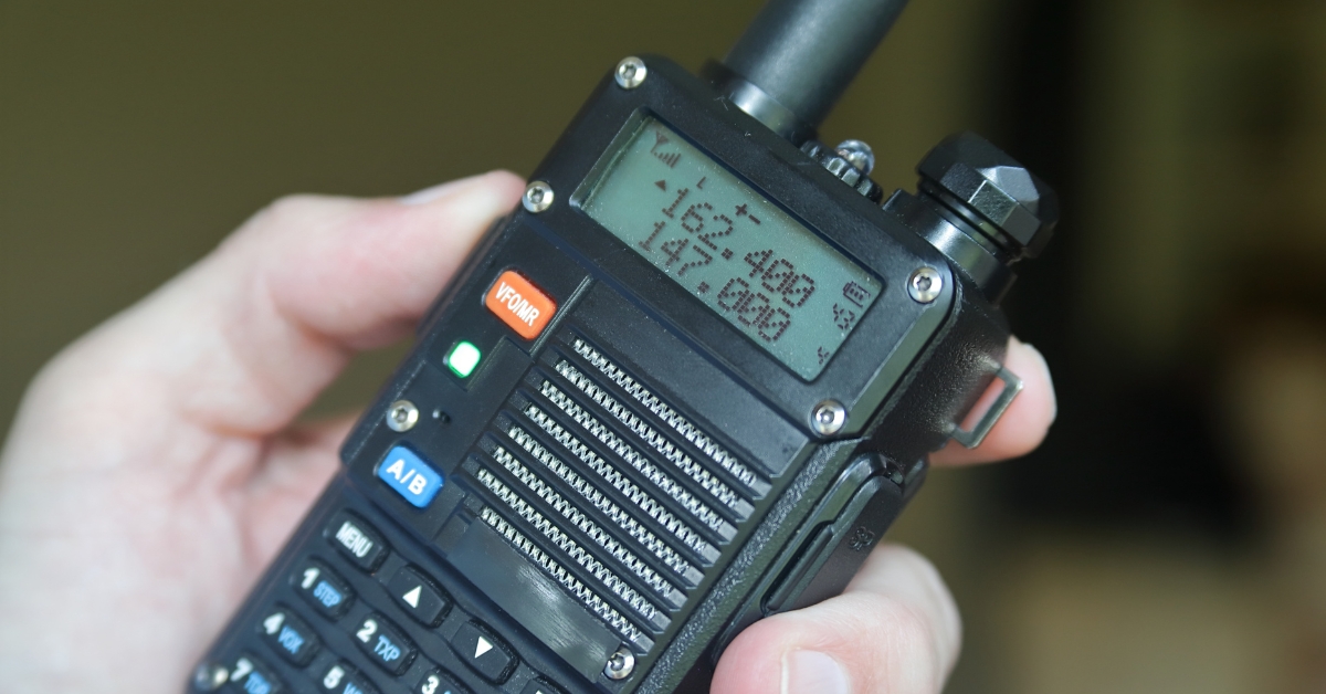 A hand holding a black radio handset