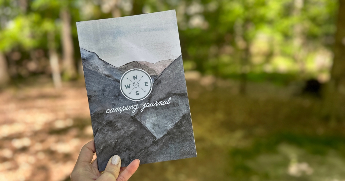 a hand holding a camping journal
