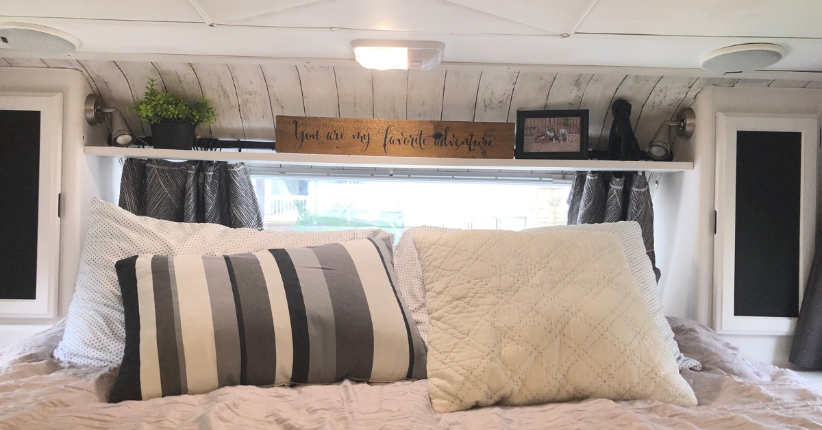 a truck camper cabover bedroom bed with pillows and a decorative shelf