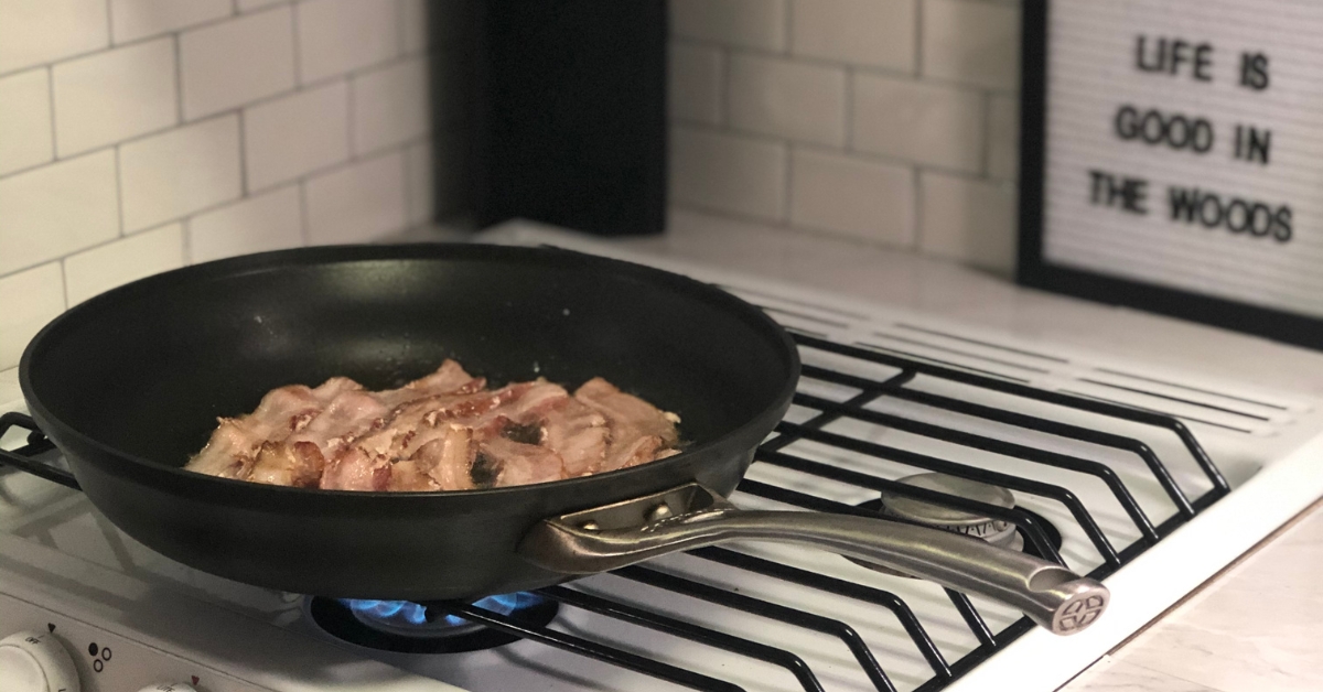 Bacon cooking on a propane gas stovetop in an RV