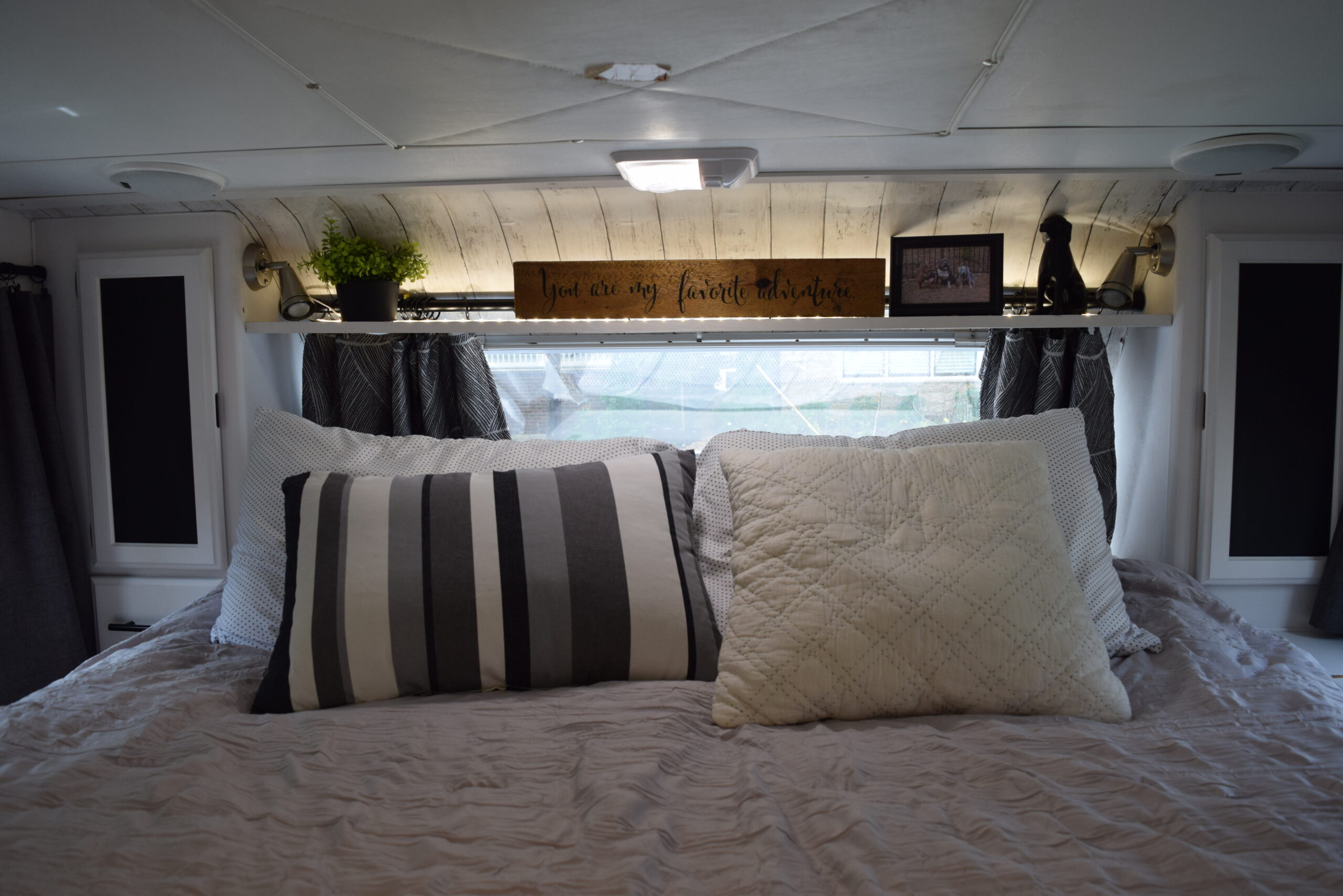 a truck camper cabover bedroom bed with pillows and a decorative shelf