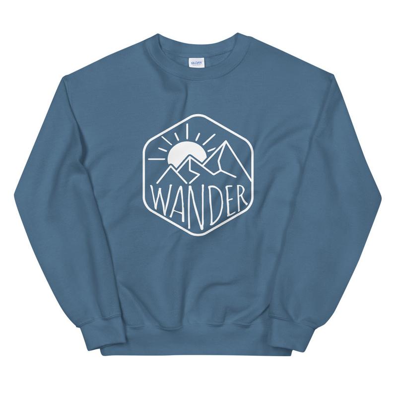 Blue sweatshirt with a mountain graphic and the word wander on it