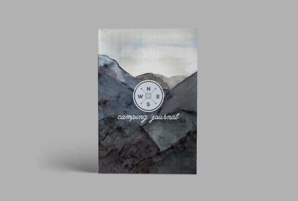 A camping journal with blue and gray watercolor mountains on the cover