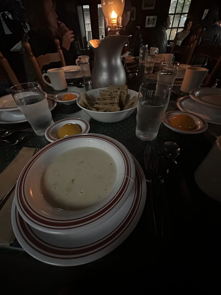 A soup bowl and other dishes at a dark dining table.