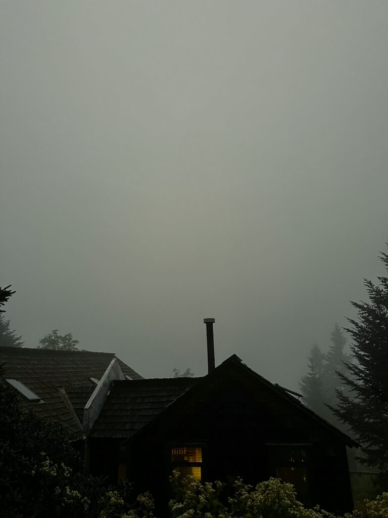 Heavy fog lowering visibility of LeConte Lodge, creating a moody photo of the dark outline of the lodge dining hall