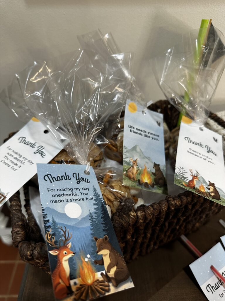 A basket with bagged s'more snack mix wrapped in woodland-themed gift tags that say thank you for making my day onedeerful. you made it s'more fun!