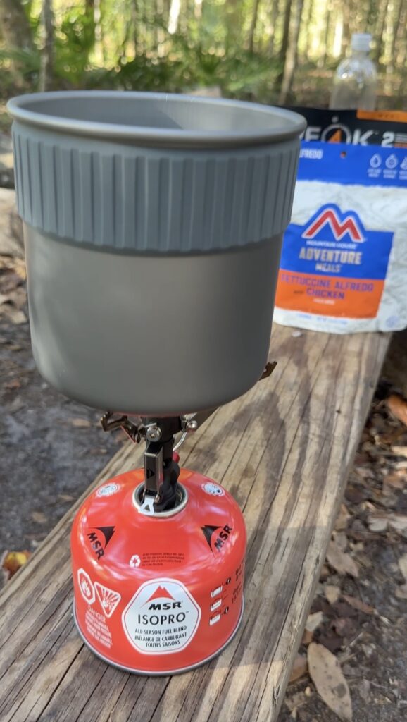 A small cookstove on a log at a campsite