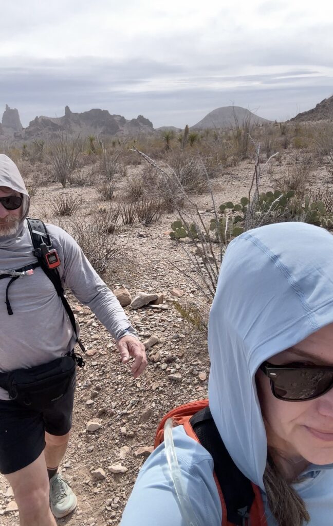 A man and woman hikingin the desert wearing sun hoodies
