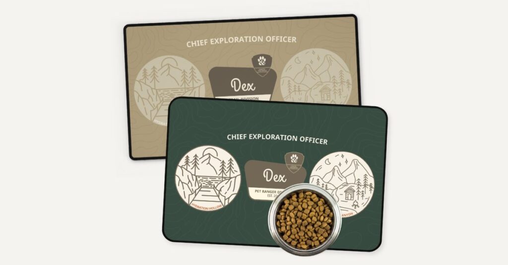 A set of two placemats, one beige and one green. a dog food bowl is placed on top of the green one. both placemats have a design of a national park sign with the words chief exploration officer at the top of the placemat. the national park sign has the pet's name and pet ranger division.